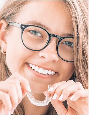 Woman with glasses holding clear retainer