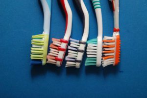 Five toothbrushes lined up in a row laying on a blue background
